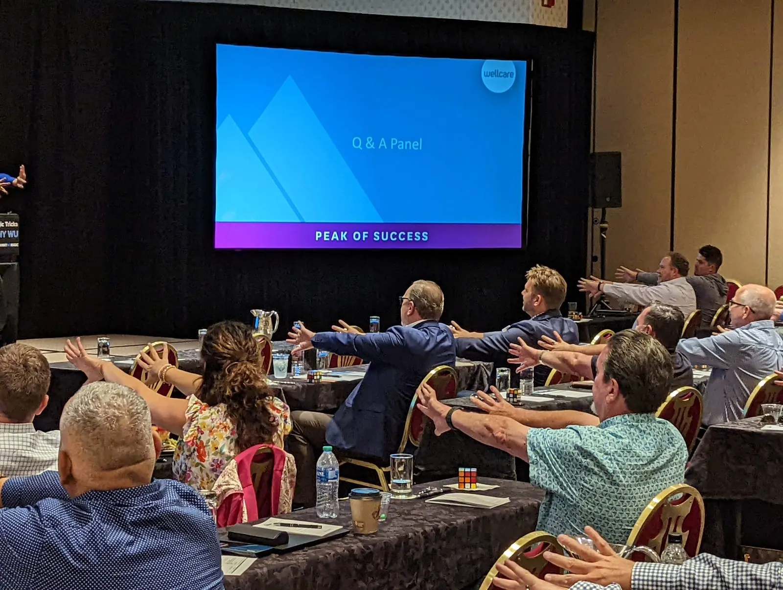 A full sales conference audience at The Broadmoor with arms stretched out in unison during an experiential keynote by Johnny Wu